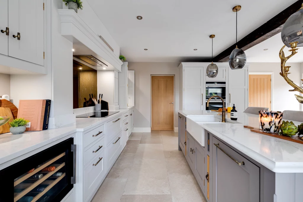 Bright modern kitchen with white cabinetry, marble countertops, central island with farmhouse sink and pendant lights.