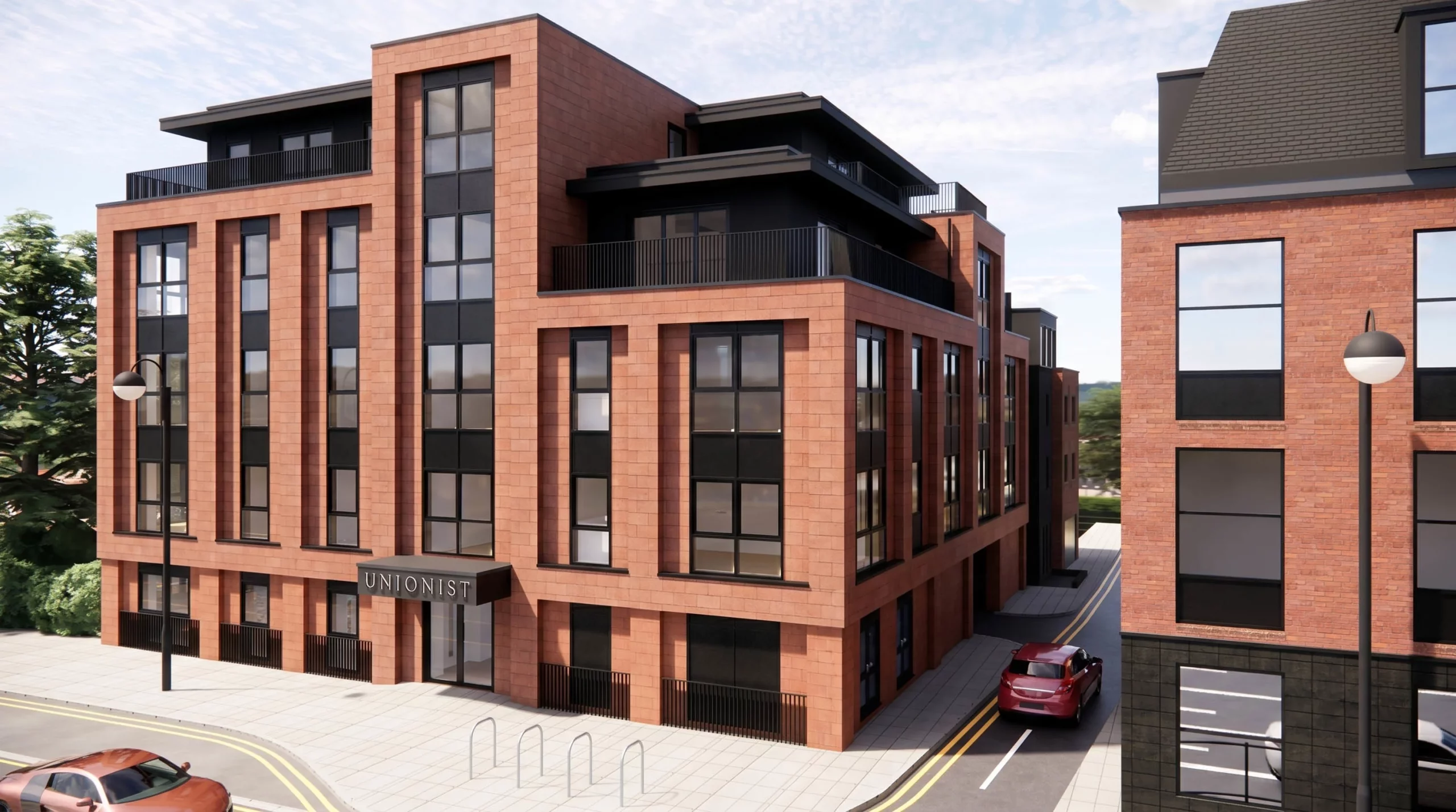 Modern red-brick mixed-use building with tall black-framed windows, rooftop terraces and a street-level entrance sign reading UNIONIST.